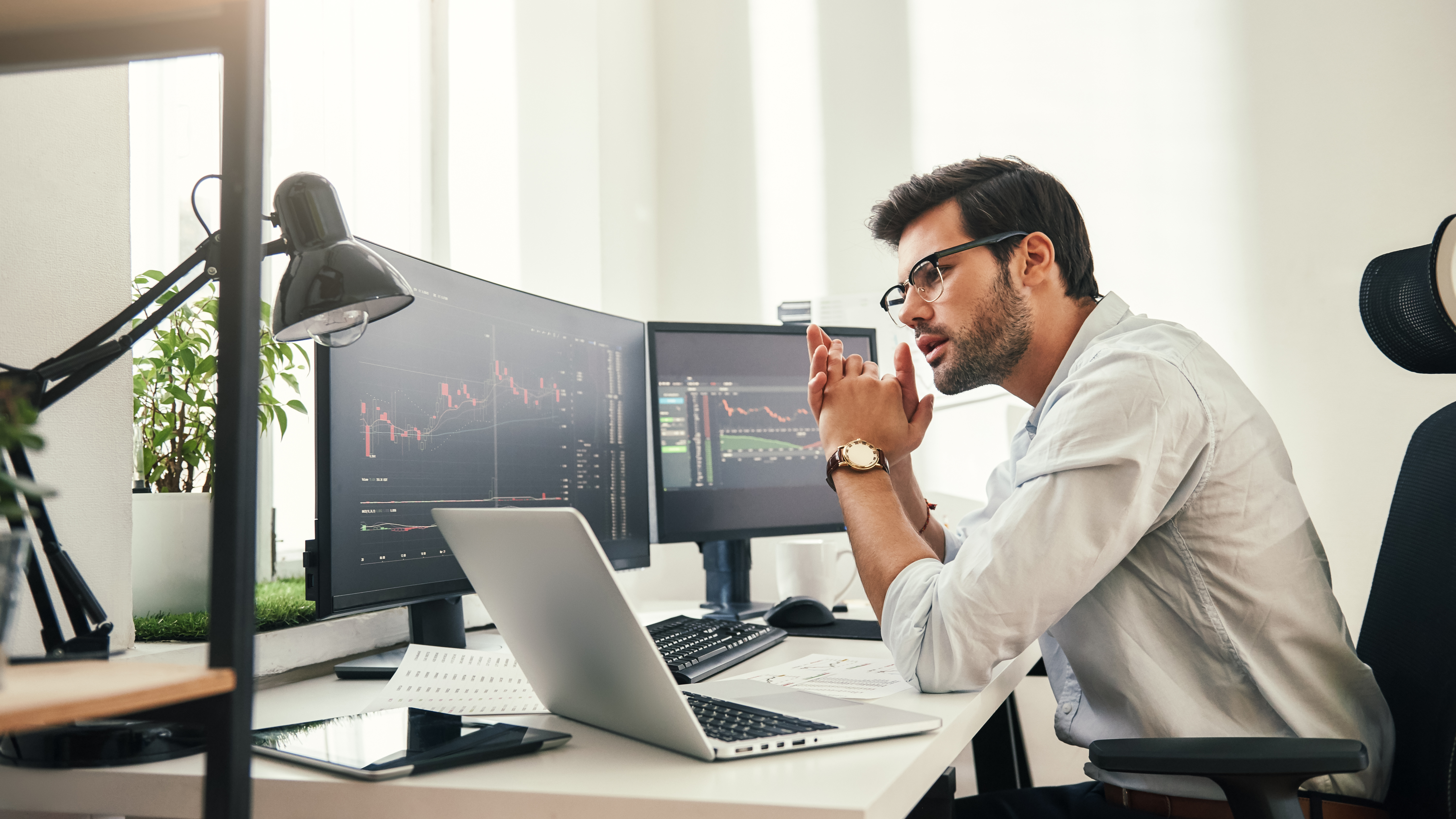 Trading strategy. Successful young trader in eyeglasses looking at analyzing trading charts on